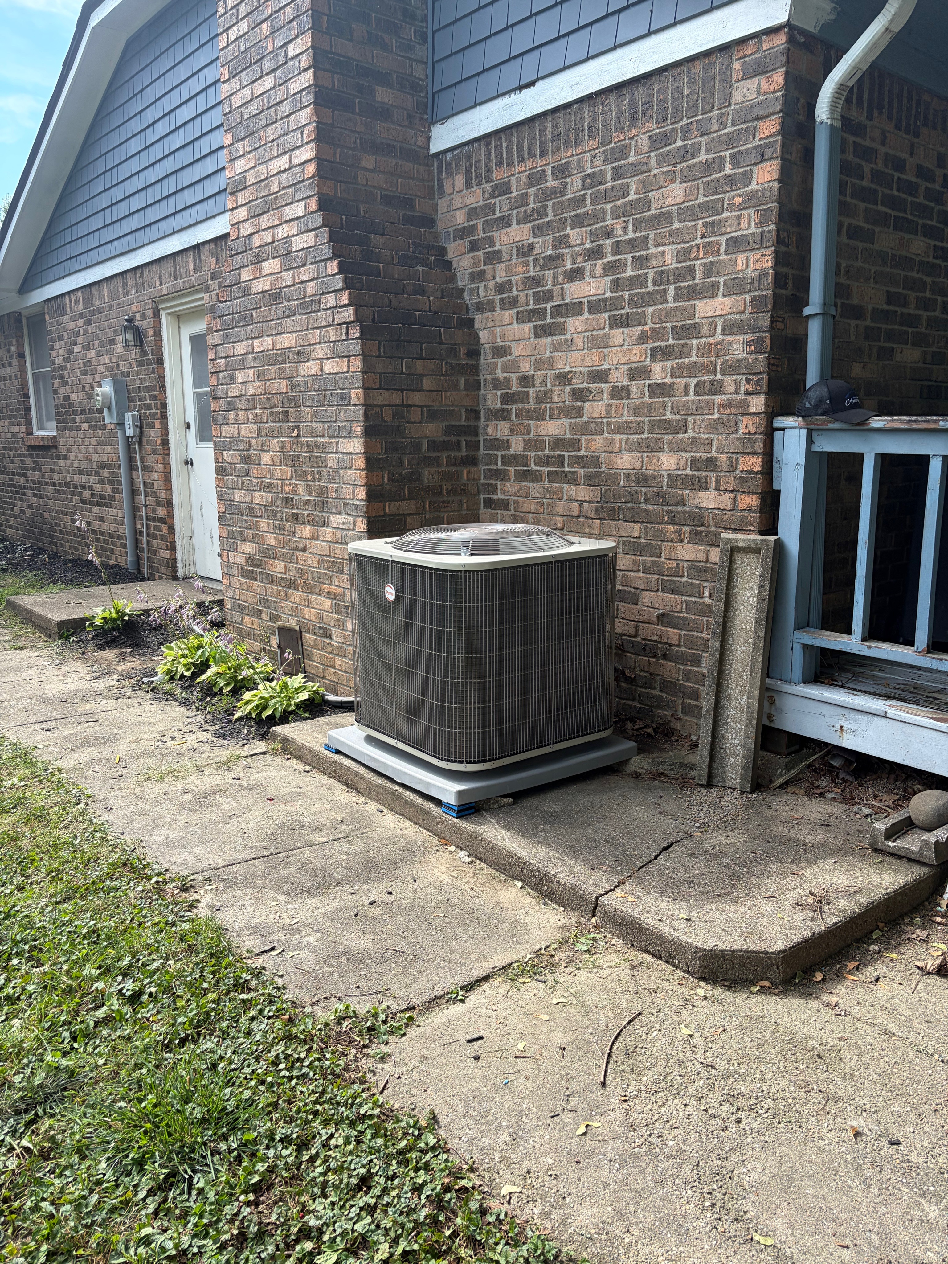 Payne AC condenser installed beside a brick home