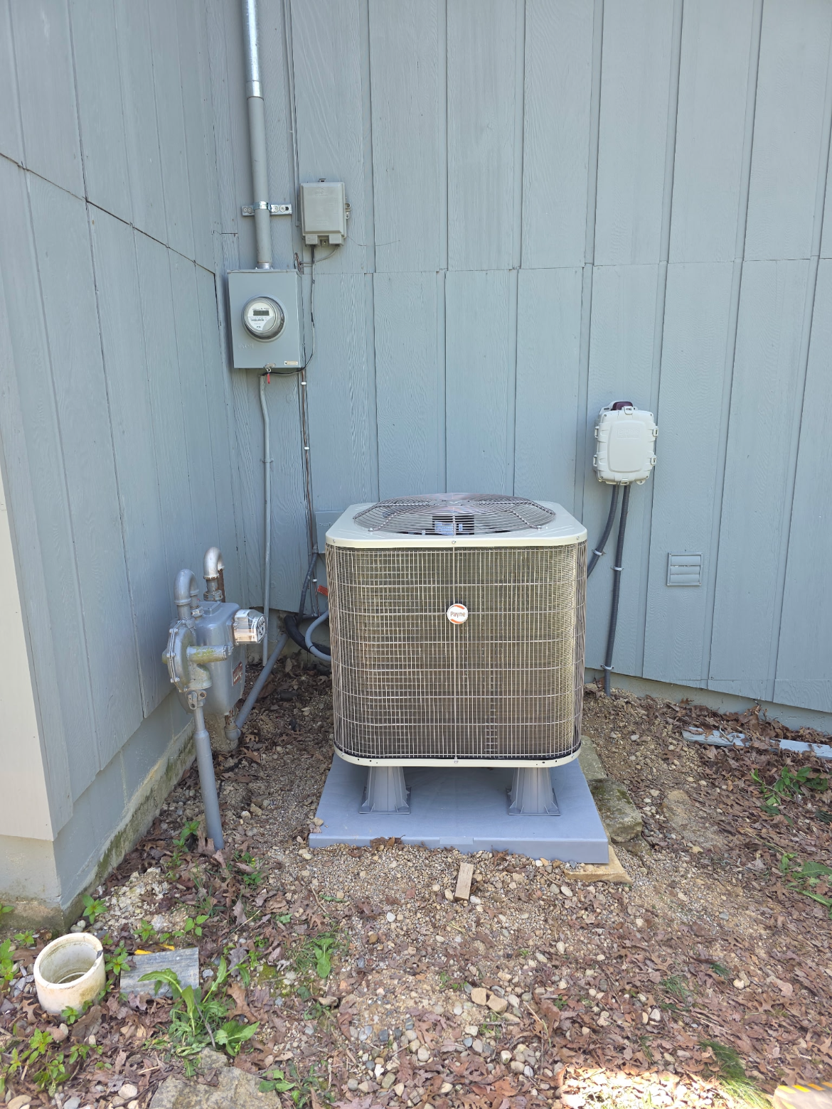 New Payne AC condenser on a pad beside a home
