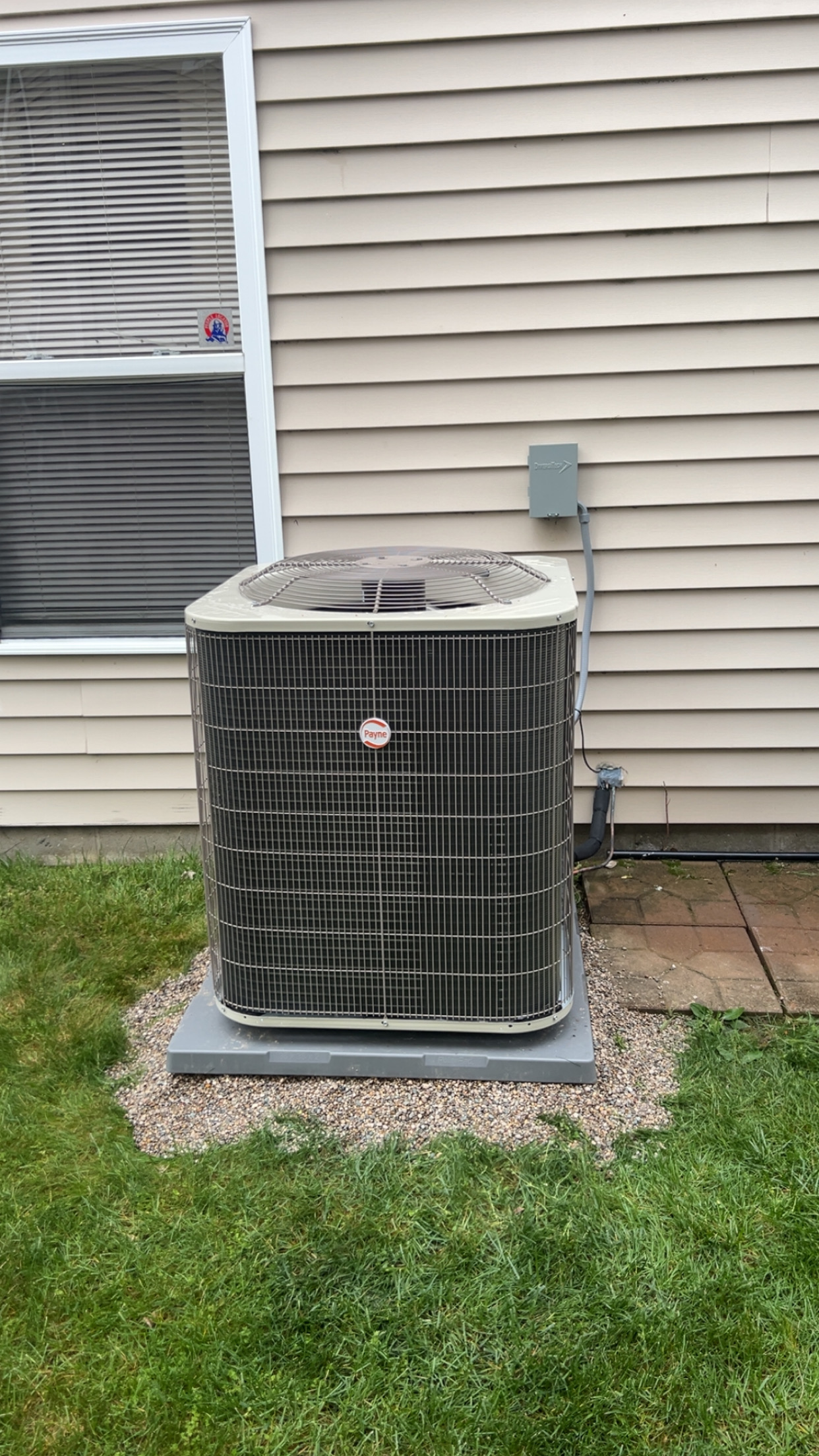 Payne AC condenser installed beside a home