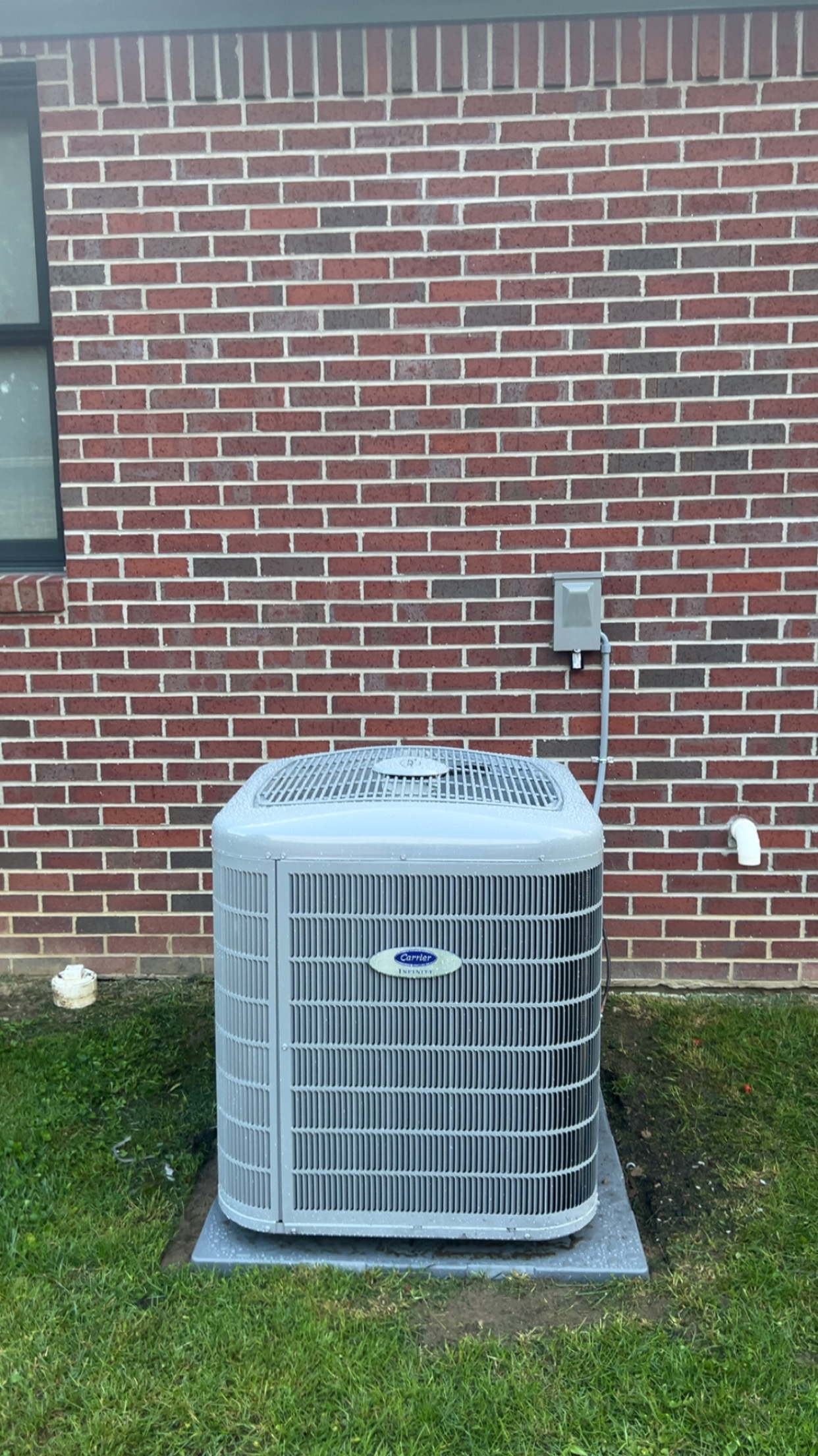 Carrier Infinity AC condenser installed at a brick home